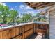 A wooden balcony overlooks a parking area and lush greenery, with a partial view of the sky above at 381 S Ames St # E104, Lakewood, CO 80226