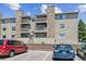 Apartment complex with stone accents, balconies, and parking, set against a blue sky backdrop at 381 S Ames St # E104, Lakewood, CO 80226