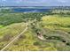 Aerial view of a grassy landscape featuring green fields, trails, and blue lake in the distance at 14064 E Whitaker Dr, Aurora, CO 80015