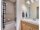 Full bathroom with neutral tile, soaking tub, vanity with storage, and updated lighting fixtures at 14064 E Whitaker Dr, Aurora, CO 80015