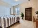 Cozy bedroom with neutral walls, carpet floors, large closet, shelving, and a queen bed with striped bedding at 14064 E Whitaker Dr, Aurora, CO 80015