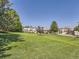Spacious front yard with large green lawn and mature trees surrounding luxury homes at 14064 E Whitaker Dr, Aurora, CO 80015