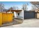 View of a detached two-car garage with modern gray doors, light brick, and a covered carport connected to the main house at 1282 S Sherman St, Denver, CO 80210