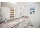 Spacious bathroom with a granite countertop, large mirror, and white cabinetry at 16278 E 111Th Pl, Commerce City, CO 80022