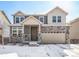 Charming two-story home featuring a stone facade, attached garage, and a snowy front yard at 16278 E 111Th Pl, Commerce City, CO 80022