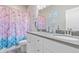 Colorful bathroom with a double sink vanity, pink and purple shower curtain, and matching decor at 11250 Florence St # 30B, Commerce City, CO 80640