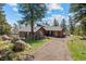 Exterior of the home showing the wood exterior, mature landscaping, and driveway at 8453 S Scenic Dr, Morrison, CO 80465
