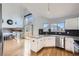 Well-lit kitchen with white cabinets, granite countertops, stainless steel appliances, and views of the living spaces at 6464 S Swadley Way, Littleton, CO 80127
