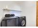 Modern laundry room with front loading Samsung washer and dryer and a shelf for storage at 6464 S Swadley Way, Littleton, CO 80127