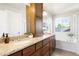 Bathroom featuring dual sinks, granite countertops, and a soaking tub with natural light at 2161 Willow Ct, Denver, CO 80238