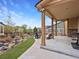 Covered back patio with wood pillars, a gray outdoor couch and two gray chairs, surrounded by landscaping at 2463 Tavern Way, Castle Rock, CO 80104