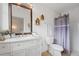 Bathroom featuring a white vanity with a large mirror, decorative shelves, and a shower with gray curtain at 8112 Gray Ct # 394, Arvada, CO 80003