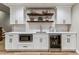 Finished basement wet bar with white cabinets, open shelving, stainless steel appliances, and subway tile backsplash at 5411 Edenborn Way, Castle Rock, CO 80104