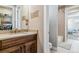 Bathroom with a double sink, wood vanity, stone countertop and a tub with tile surround at 5411 Edenborn Way, Castle Rock, CO 80104