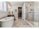Bright bathroom featuring a soaking tub, walk-in shower, dual sinks, and a pass-through to a large walk-in closet at 5411 Edenborn Way, Castle Rock, CO 80104