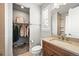 Modern bathroom vanity with an open closet featuring hanging clothes and shelving at 5411 Edenborn Way, Castle Rock, CO 80104