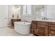 Bright bathroom featuring a soaking tub, dual sinks with dark wood cabinets, and a window with shutter-style blinds at 5411 Edenborn Way, Castle Rock, CO 80104