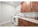 Laundry room with modern appliances, wood cabinets, patterned tile floors, and sink at 5411 Edenborn Way, Castle Rock, CO 80104