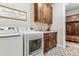 Laundry room with wood cabinets, tile floor, and new washer and dryer at 5411 Edenborn Way, Castle Rock, CO 80104