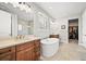 Spa-like main bathroom with dual vanities, freestanding tub, walk-in shower, and access to a walk-in closet at 5411 Edenborn Way, Castle Rock, CO 80104