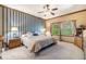 Comfortable bedroom features a ceiling fan, a large window with a wooded view and blue and white striped wall at 9873 Greensview Cir, Lone Tree, CO 80124