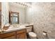 Charming half bathroom with patterned wallpaper and a vanity with ample counter space at 9873 Greensview Cir, Lone Tree, CO 80124