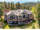 Stunning aerial view of a luxurious home with a spacious deck and beautiful mountain backdrop at 26886 Evergreen Springs Rd, Evergreen, CO 80439