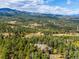 An aerial view shows the house surrounded by stunning mountain views and abundant trees at 26886 Evergreen Springs Rd, Evergreen, CO 80439