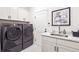 Contemporary laundry room featuring gray washer and dryer set, white cabinetry, and modern faucet at 1026 Deer Clover Way, Castle Pines, CO 80108