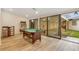 Bright game room with a pool table, arcade machine, wood floors, and sliding glass doors to the backyard patio at 3550 Eudora St, Denver, CO 80207