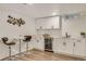 Basement kitchenette with white cabinets, stainless steel beverage cooler, marble countertops and stylish barstool seating at 3550 Eudora St, Denver, CO 80207