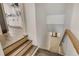 View of an indoor staircase with wood steps leading to a bright, remodeled kitchen with white cabinets and hardwood floors at 3550 Eudora St, Denver, CO 80207