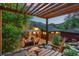 Relaxing backyard patio with a pergola, seating, and lush green landscaping at 2874 Se Grapevine Rd, Idledale, CO 80453
