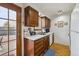 Functional kitchen with wood cabinets, bright countertops, tile floor and outdoor access to a stone patio at 4641 W Ponds Cir, Littleton, CO 80123