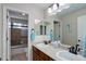 Well-lit bathroom featuring double sinks, wood cabinets and shower-tub with tile surround at 6078 Bridle Path Ln, Parker, CO 80134