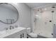 Modern bathroom with a glass shower, round mirror, vanity, toilet and gray tile flooring at 6078 Bridle Path Ln, Parker, CO 80134