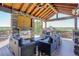 Beautiful outdoor covered living area with a stone fireplace and comfortable seating overlooking a green landscape at 6078 Bridle Path Ln, Parker, CO 80134