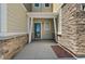 Covered front porch with stone accents and a modern front door welcomes you home at 9719 Albion Ln, Thornton, CO 80229