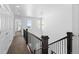 Upstairs hallway with dark railings, neutral walls, and two windows providing natural light at 9719 Albion Ln, Thornton, CO 80229