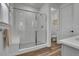 Modern bathroom featuring a glass-enclosed shower with white subway tile and wood-look flooring at 8728 Hotchkiss St, Littleton, CO 80125