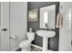 Modern bathroom features a stylish pedestal sink, dark accent wall, and updated fixtures at 8728 Hotchkiss St, Littleton, CO 80125