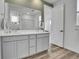 Bright bathroom with double vanity, wood floors, and a door leading to the main bedroom at 8728 Hotchkiss St, Littleton, CO 80125
