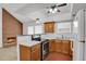Open kitchen layout with wood cabinets, bar seating, and modern stainless steel appliances at 3300 W Florida Ave # 26, Denver, CO 80219
