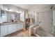 Bright bathroom featuring double sinks, granite counters, and a glass shower with a bench at 7515 Pineridge Trl, Castle Pines, CO 80108