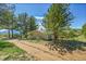 View of home surrounded by mature trees and dirt driveway at 258 Post Boy Rd, Boulder, CO 80302