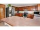 Kitchen with stainless steel refrigerator and appliances, brown cabinets, and breakfast bar counter at 4111 W Kenyon Ave, Denver, CO 80236