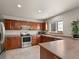 Well-lit kitchen features wooden cabinets, tile flooring, stainless steel appliances, and eat in breakfast bar at 4111 W Kenyon Ave, Denver, CO 80236