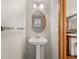 Charming powder room featuring a pedestal sink, oval mirror, and neutral tones at 4111 W Kenyon Ave, Denver, CO 80236