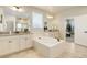 Bright bathroom with double vanity, a soaking tub, and views of the bedroom at 7099 E 123Rd Pl, Thornton, CO 80602