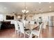 Open-concept dining area with wood floors, modern lighting, and seamless flow to the kitchen and living room at 7099 E 123Rd Pl, Thornton, CO 80602